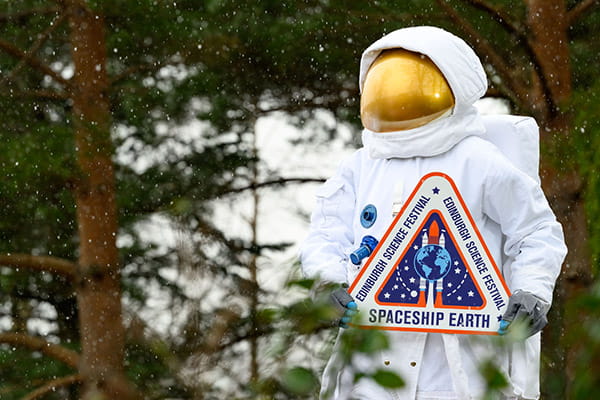 Spaceman holding the Edinburgh Science Festival sign