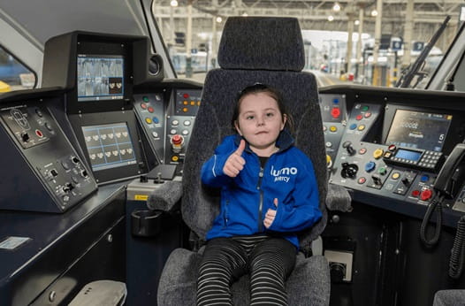 child sat on train drivers seat